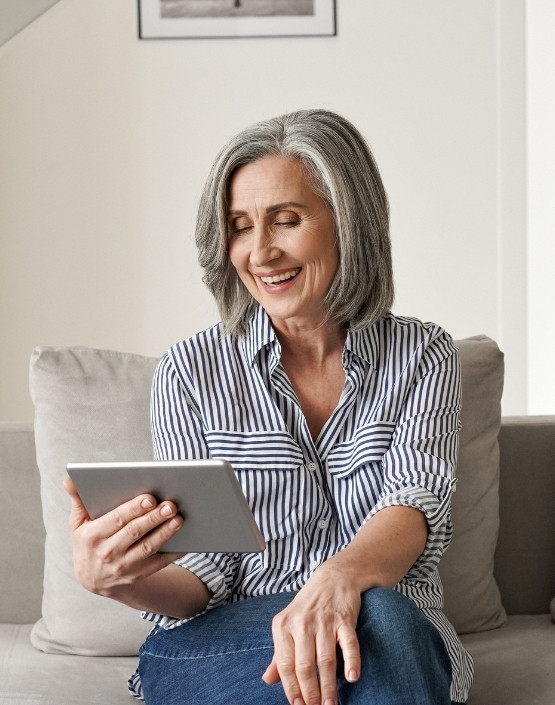 An older woman smiling while using her tablet